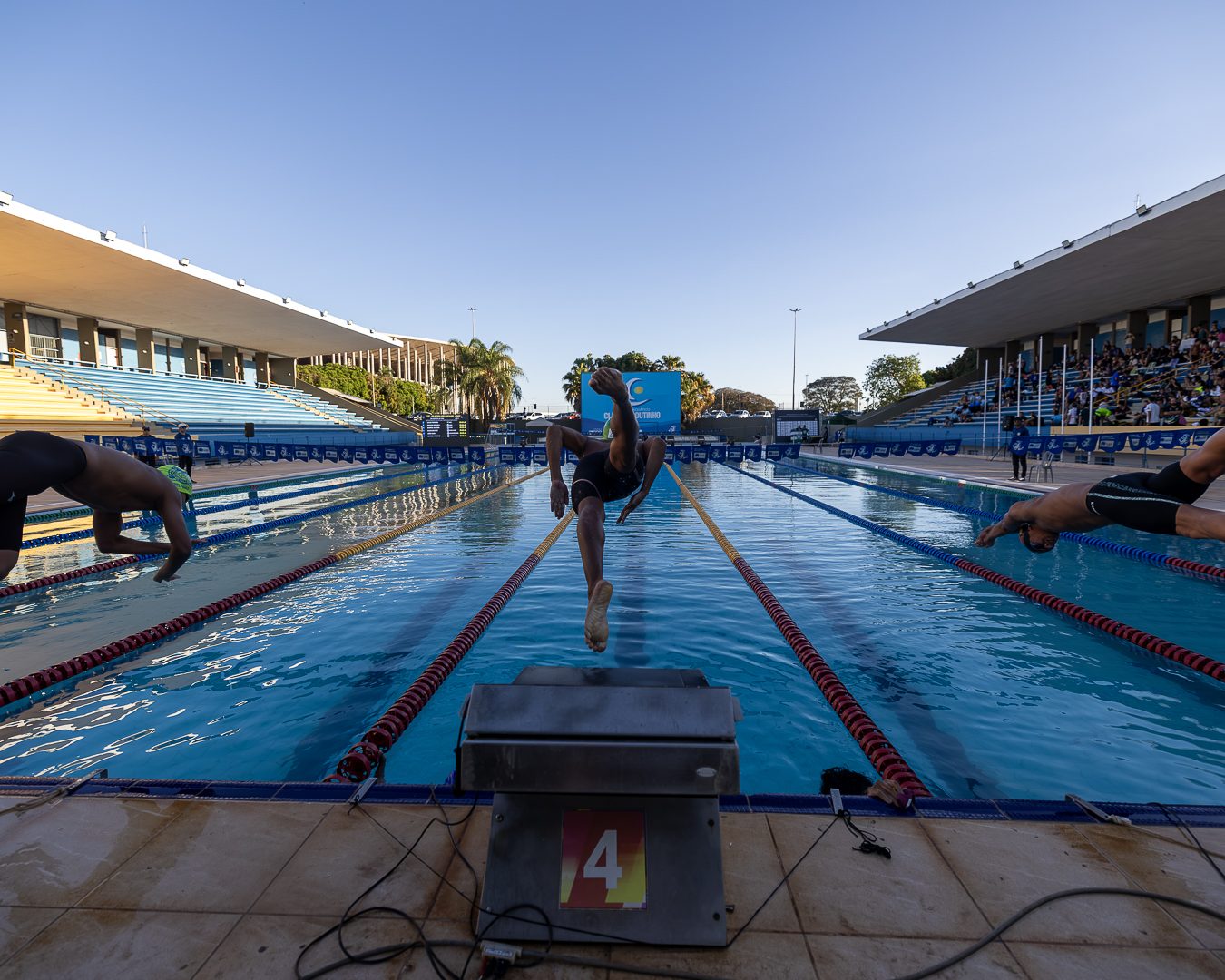 Vista da piscina de 50 metros do Complexo Aquático Cláudio Coutinho a partir da cabeceira, com o céu de fim de tarde
