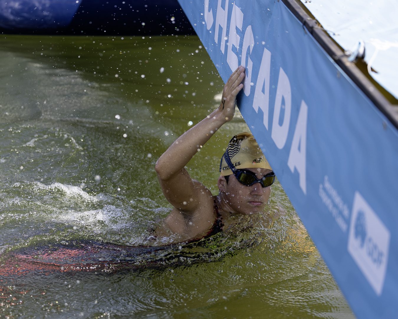 Nadador toca a placa de chegada azul ao fim da prova de 4 km