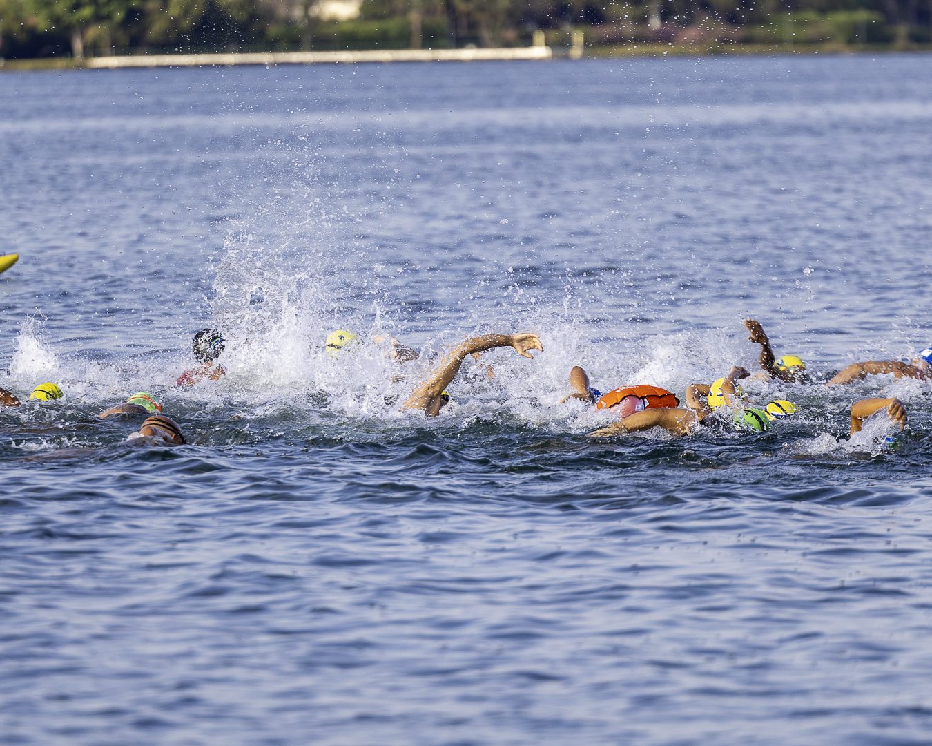 Nadadores largam em grupo no Lago Paranoá, com toucas amarelas e verdes, durante a Copa Brasil de Águas Abertas
