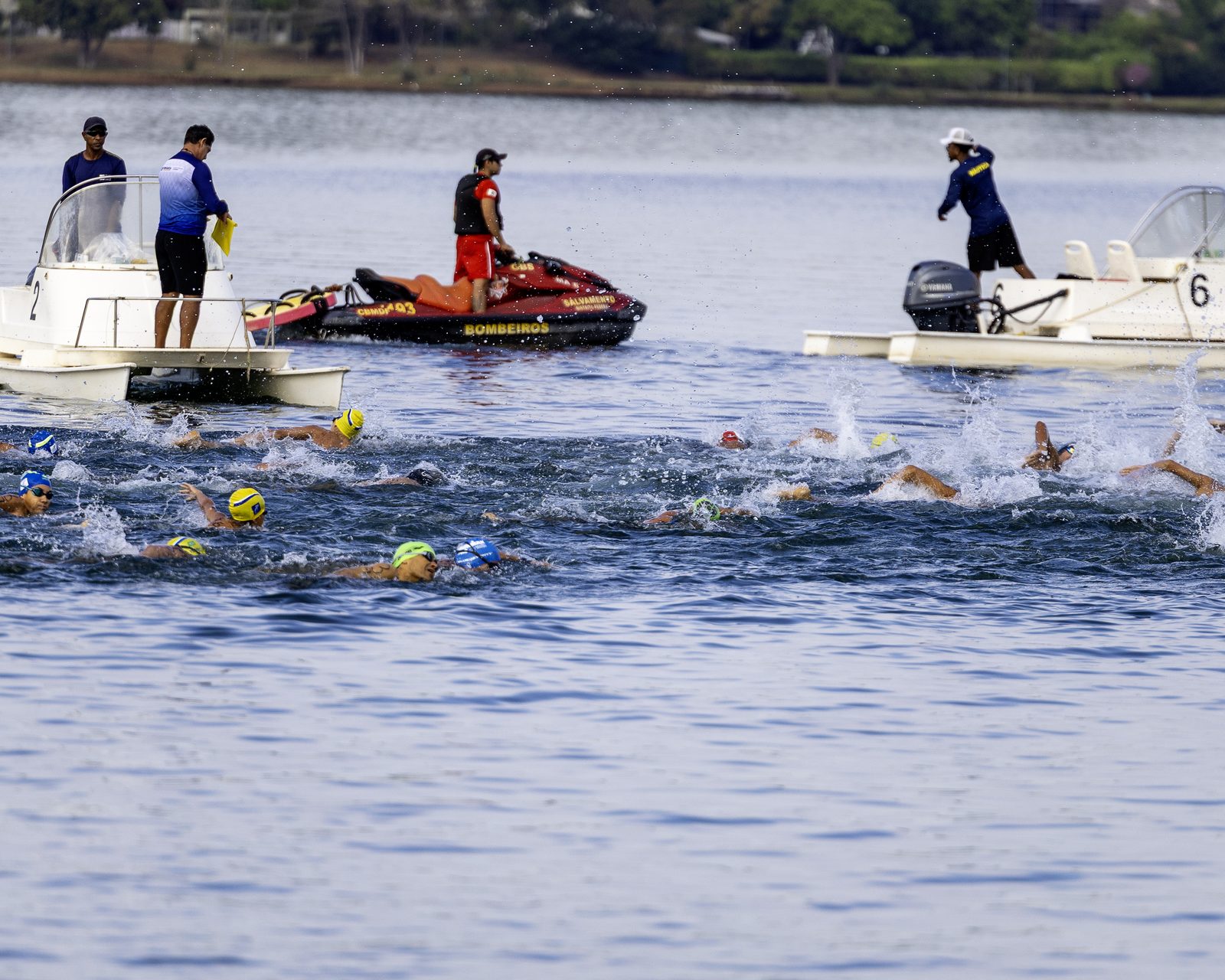 Largada da prova de 2,5 km no Lago Paranoá, com embarcações de apoio e moto aquática do Corpo de Bombeiros ao fundo
