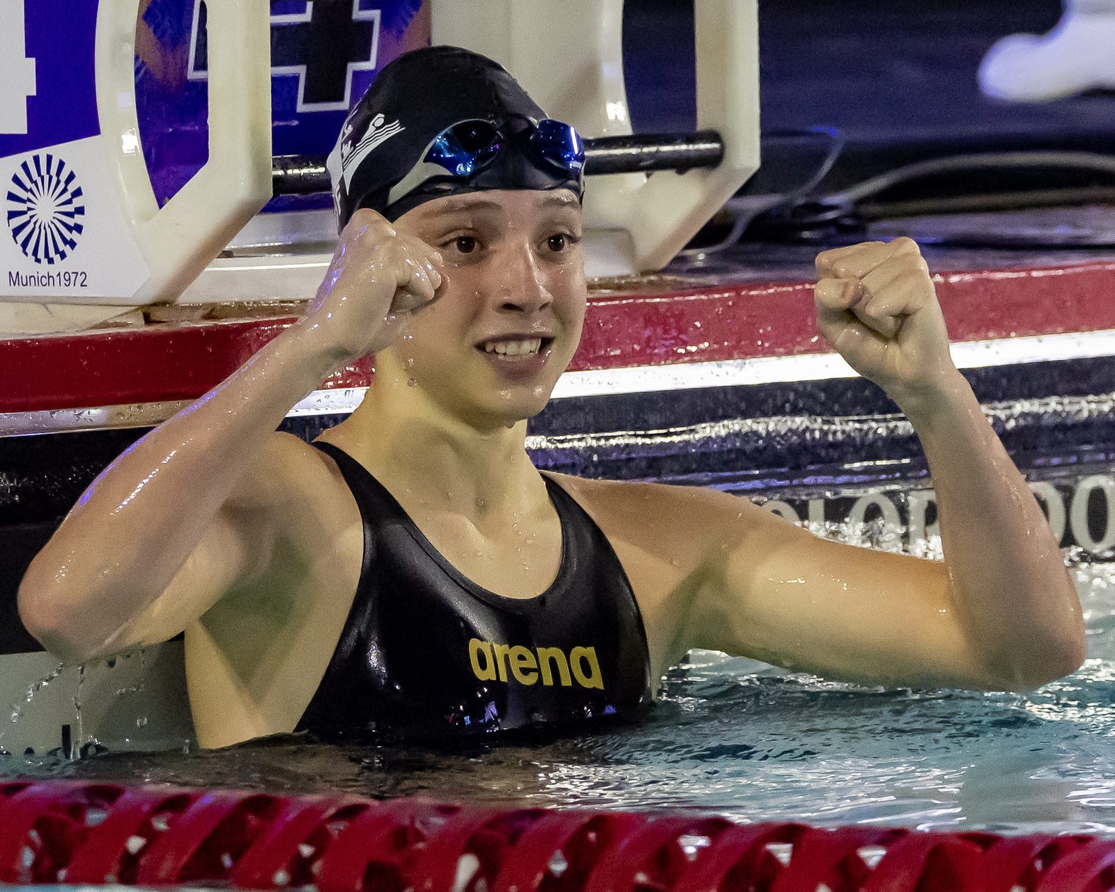 Atleta da Seleção do DF comemora dentro da piscina, de punhos cerrados, junto ao bloco de partida