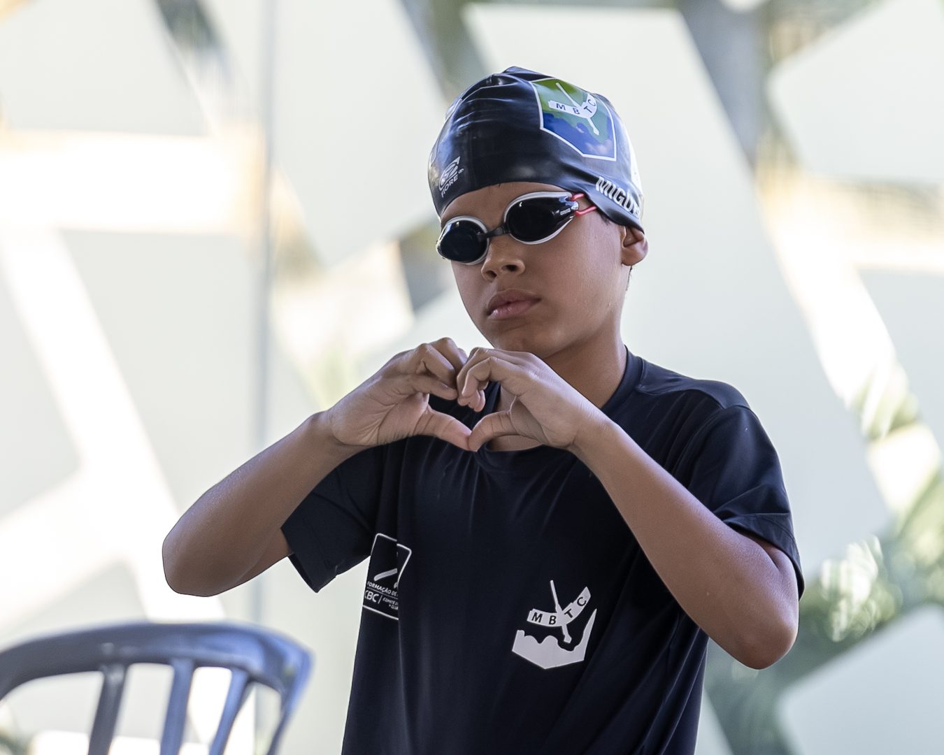 Atleta de camiseta preta e touca faz um coração com as mãos