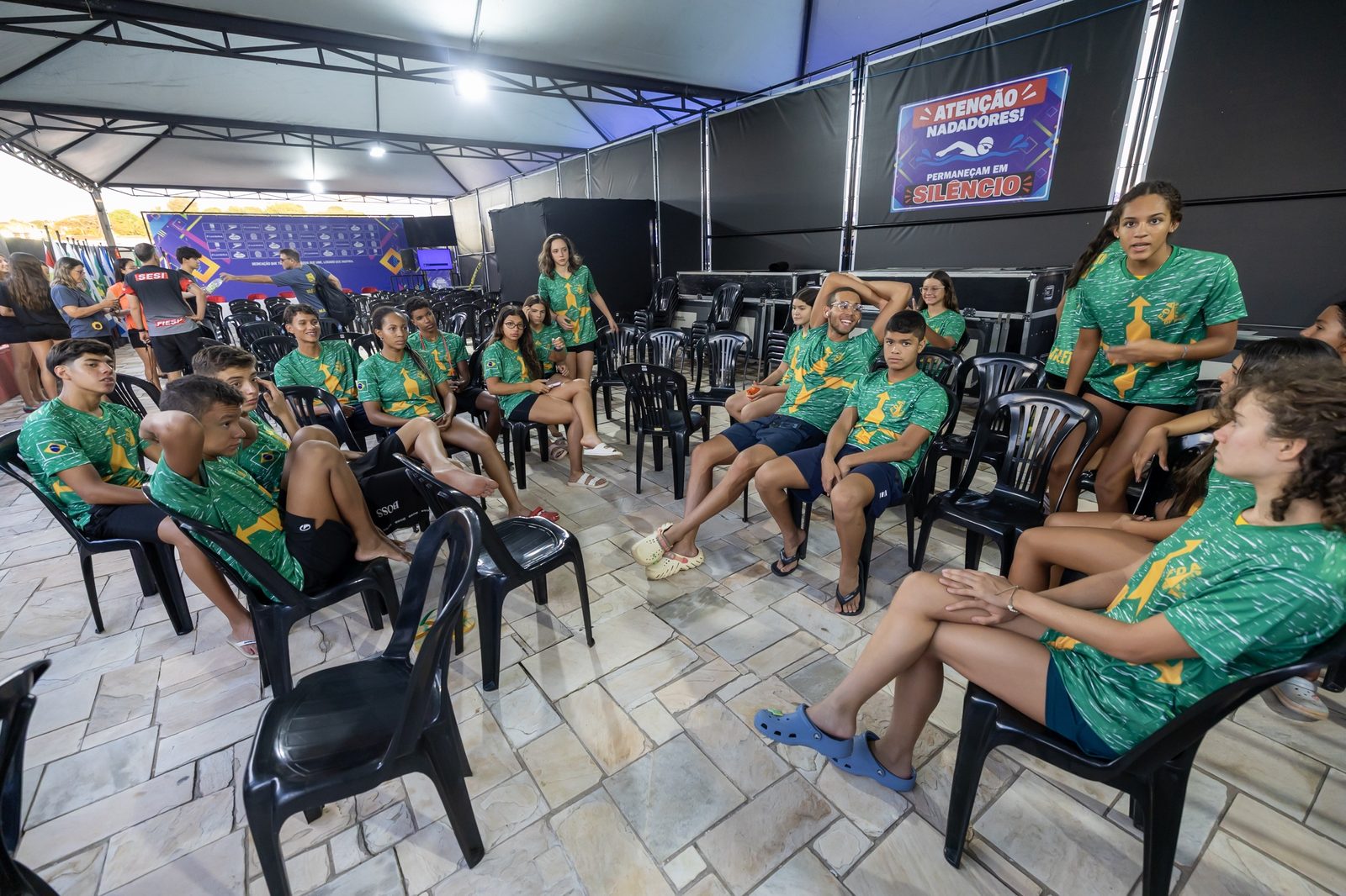 Atletas da Seleção do DF, de camisa verde e amarela, reunidos sob a tenda do clube