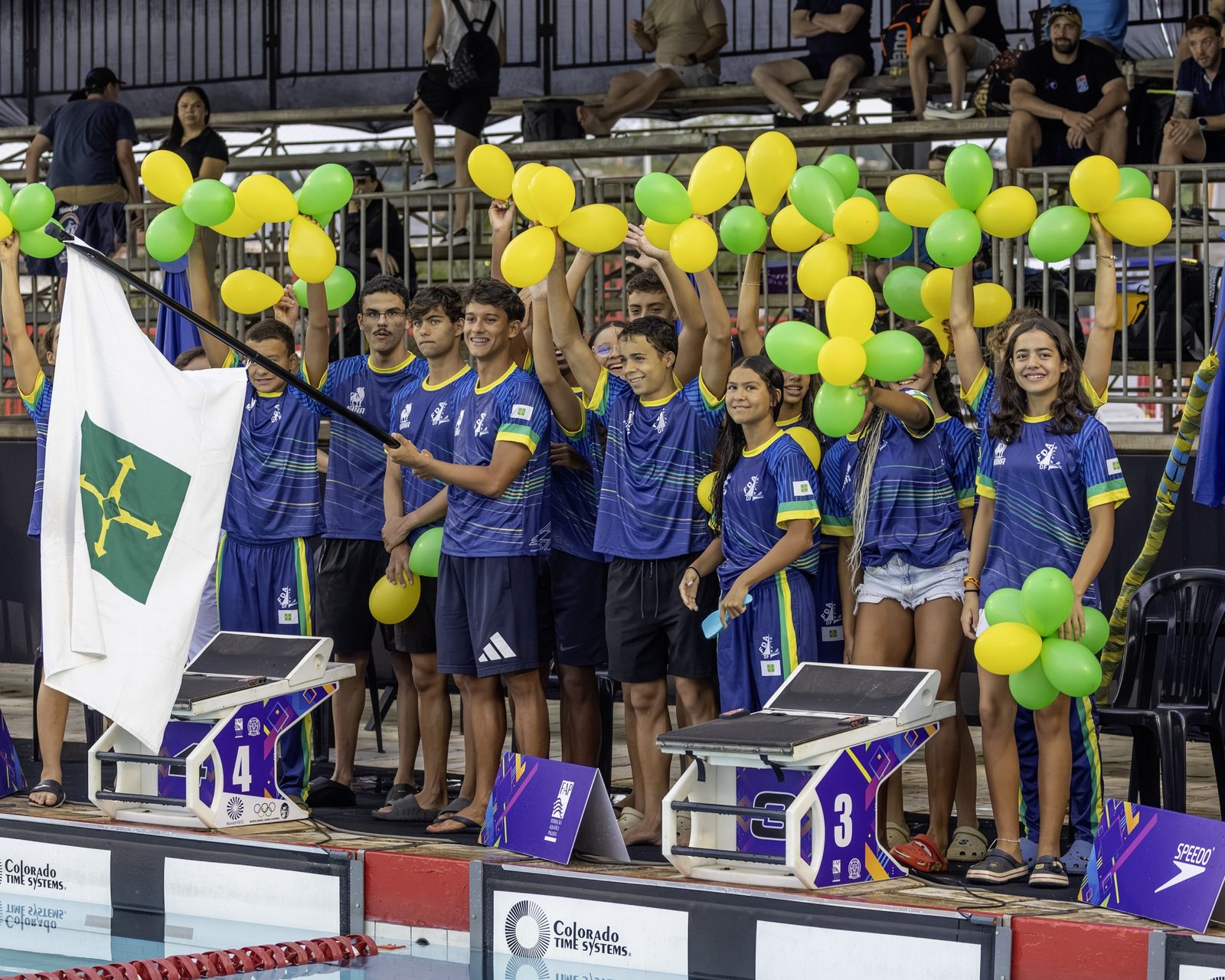 Delegação do DF na beira da piscina, com balões verdes e amarelos e a bandeira do Distrito Federal