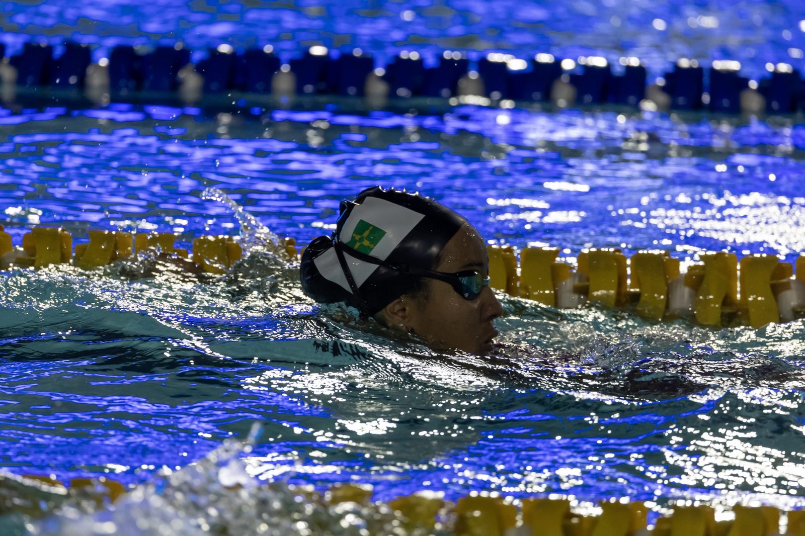 Atleta de óculos espelhados e touca da FDA-DF nada entre raias amarelas